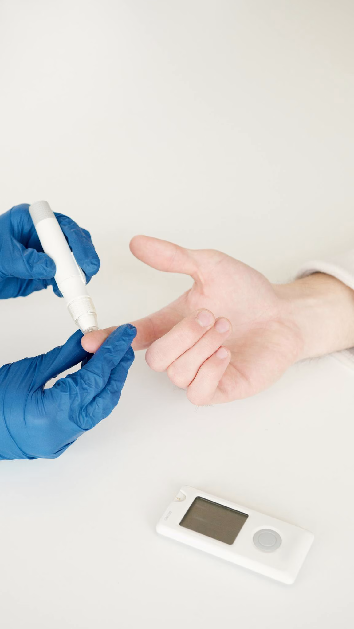 A healthcare professional tests blood sugar with a glucometer and lancet pen in a medical setting 