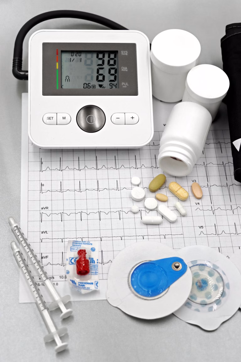 Medical setup featuring blood pressure monitor, pills, syringes, and ECG printout for healthcare themes 
